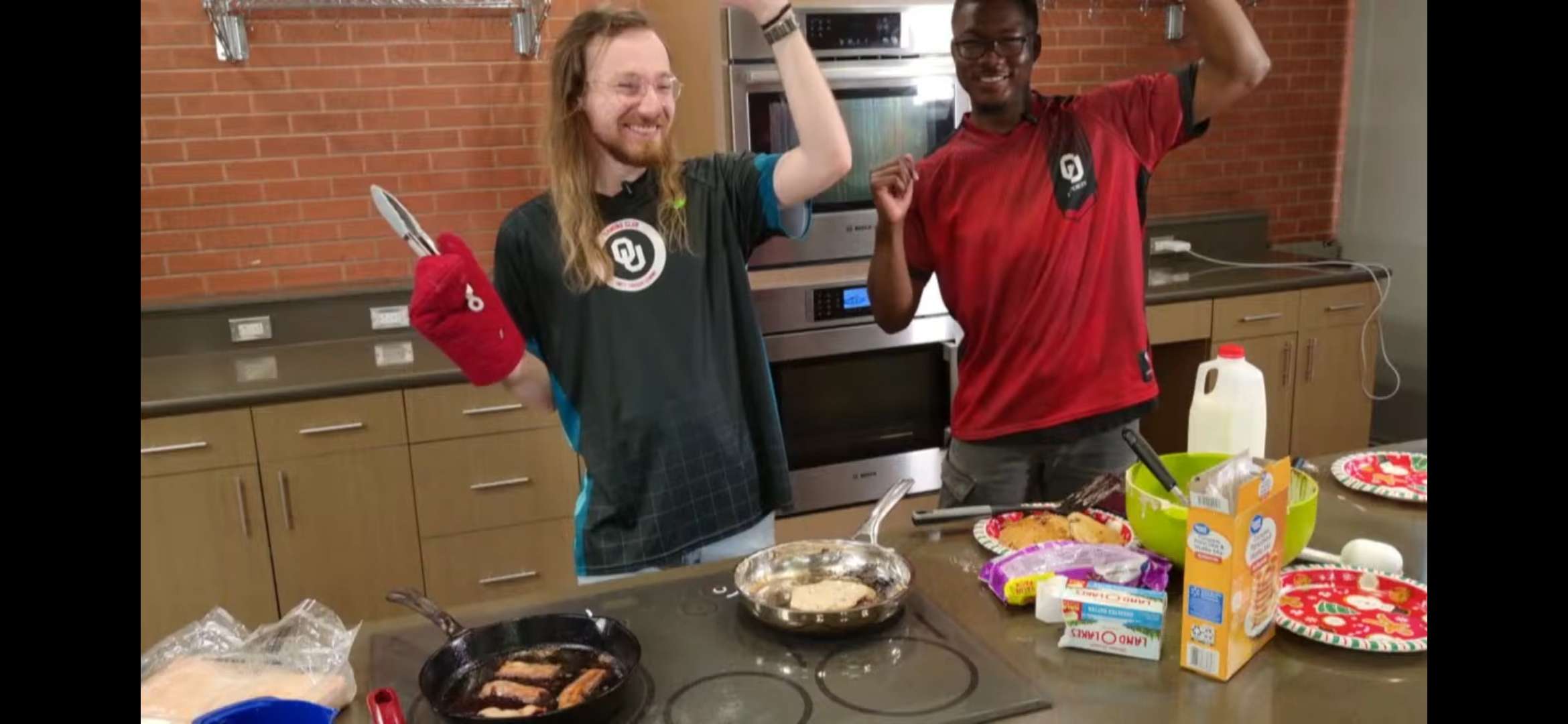 News Coordinator Will Edmonds and Media Lead Kaori Thomas raise their arms in celebration.